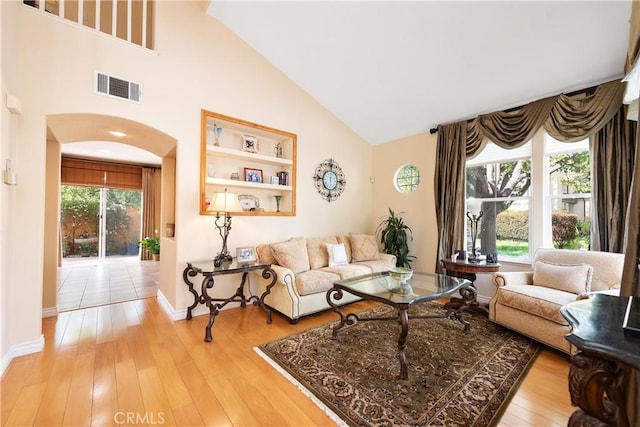 11803 Sortino Ct, Moorpark, CA 93021 - living room with arched walkways, light wood-style floors, baseboards, and high vaulted ceiling