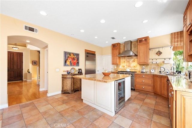 11803 Sortino Ct, Moorpark, CA 93021 - kitchen featuring wall chimney range hood, premium appliances, wine cooler, arched walkways, and a center island