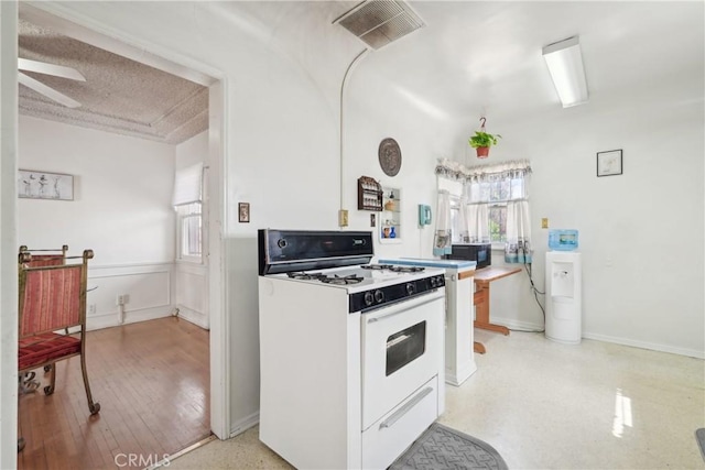 1845 W 91st Pl, Los Angeles, CA 90047 - kitchen featuring white gas stove, black microwave, healthy amount of natural light, and a ceiling fan