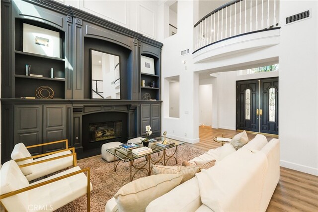 20112 Via Cellini, Porter Ranch, CA 91311 - living room with wood finished floors, baseboards, a towering ceiling, a glass covered fireplace, and built in shelves
