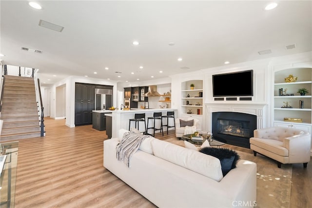 20112 Via Cellini, Porter Ranch, CA 91311 - living room featuring light wood-style flooring, stairway, recessed lighting, a glass covered fireplace, and baseboards