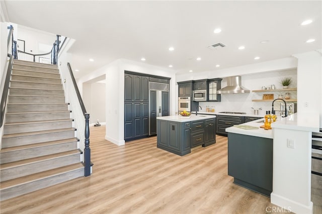20112 Via Cellini, Porter Ranch, CA 91311 - kitchen featuring built in appliances, a sink, wall chimney range hood, an island with sink, and light countertops