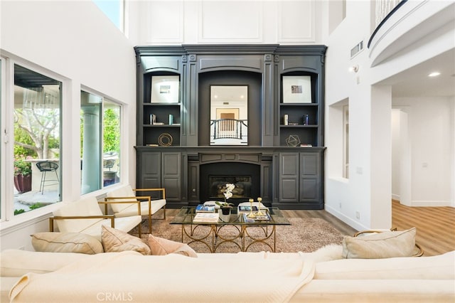 20112 Via Cellini, Porter Ranch, CA 91311 - living room featuring light wood-style flooring, a towering ceiling, a glass covered fireplace, and baseboards