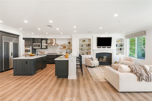 20112 Via Cellini, Porter Ranch, CA 91311 - kitchen featuring built in appliances, a kitchen island with sink, light countertops, crown molding, and wall chimney exhaust hood