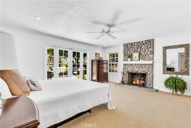 carpeted bedroom featuring multiple windows, access to exterior, a stone fireplace, and baseboards