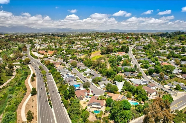 view of property location featuring a main thoroughfare, a pool, nearby suburban area, and a mountainous background