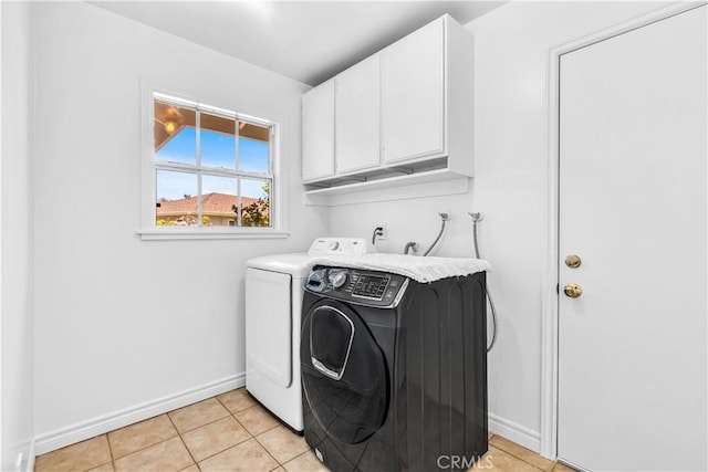laundry room featuring washing machine and dryer, cabinet space, baseboards, and light tile patterned floors