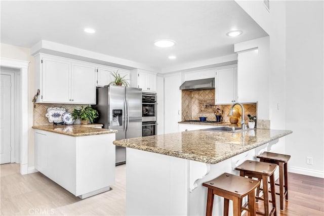 kitchen featuring a sink, a peninsula, stainless steel appliances, ventilation hood, and recessed lighting