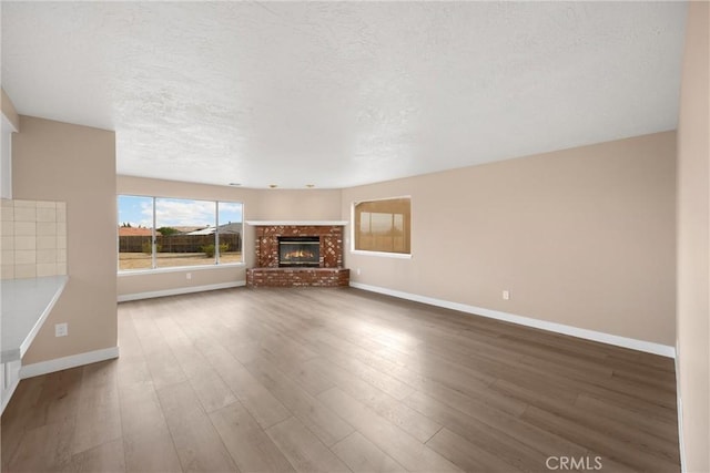 17725 Tude Ln, Apple Valley, CA 92307 - unfurnished living room with baseboards, a textured ceiling, wood finished floors, and a brick fireplace