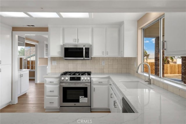 17725 Tude Ln, Apple Valley, CA 92307 - kitchen with appliances with stainless steel finishes, a sink, light stone countertops, and tasteful backsplash