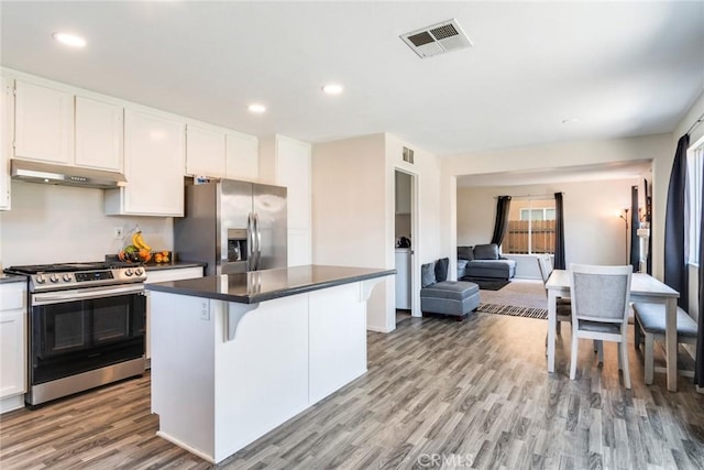 1113 Juniper Ct, San Jacinto, CA 92582 - kitchen featuring stainless steel appliances, dark countertops, under cabinet range hood, a kitchen island, and light wood-style floors