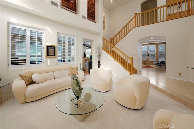 25415 Verne Ct, Stevenson Ranch, CA 91381 - living room featuring arched walkways, stairway, and a towering ceiling
