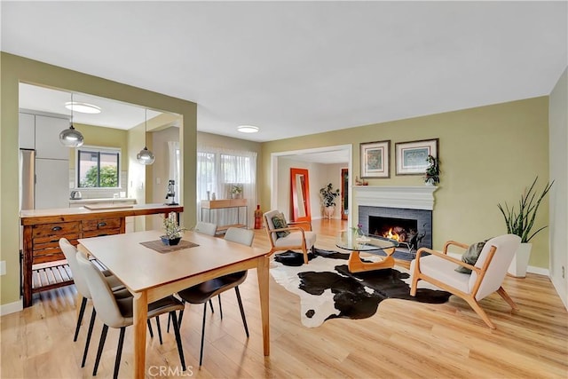 3235 Faust Ave, Long Beach, CA 90808 - dining area with light wood-type flooring, a brick fireplace, and baseboards