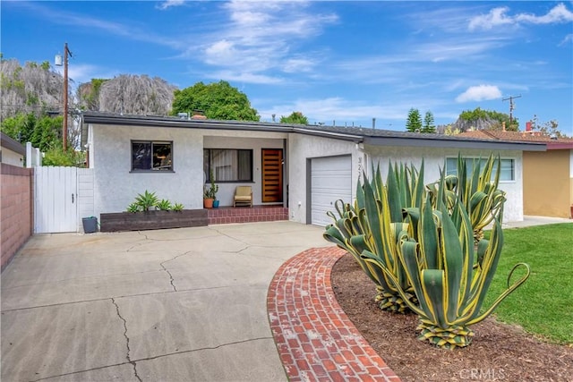 3235 Faust Ave, Long Beach, CA 90808 - view of front facade featuring stucco siding, an attached garage, driveway, and a gate