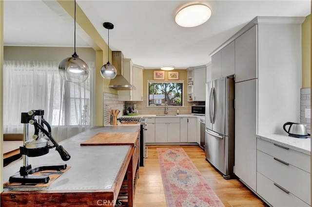 3235 Faust Ave, Long Beach, CA 90808 - kitchen with appliances with stainless steel finishes, wall chimney exhaust hood, decorative backsplash, light wood-type flooring, and hanging light fixtures
