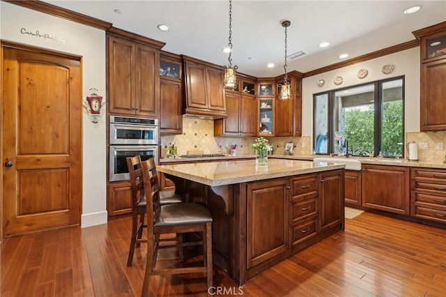 4004 Snowgoose St, Simi Valley, CA 93065 - kitchen with stainless steel appliances, a kitchen island, dark wood-type flooring, crown molding, and decorative light fixtures