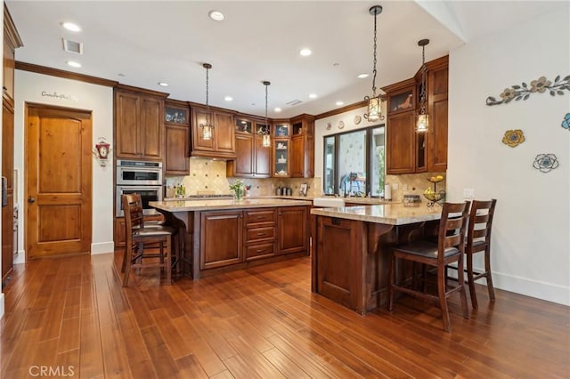 4004 Snowgoose St, Simi Valley, CA 93065 - kitchen with a kitchen bar, glass insert cabinets, baseboards, dark wood-style floors, and crown molding