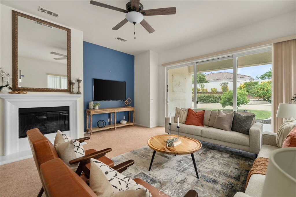 1690 Landmark Way, Beaumont, CA 92223 - carpeted living room with ceiling fan, a glass covered fireplace, and baseboards