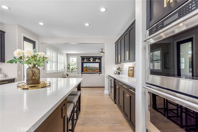 32429 Castle Ct, Temecula, CA 92592 - kitchen with stainless steel double oven, light countertops, light wood-style floors, recessed lighting, and open floor plan