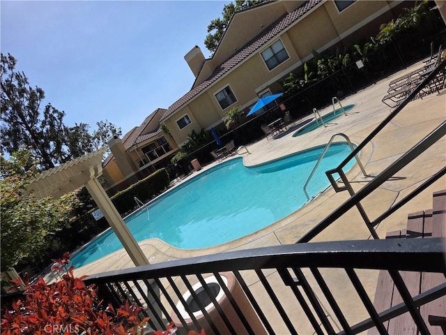 community pool with a patio and fence
