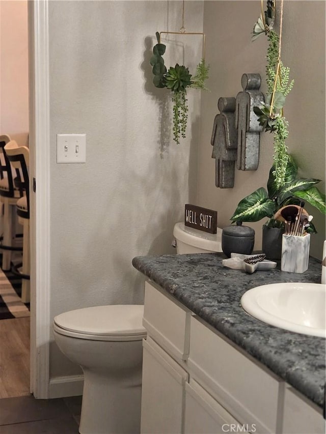 bathroom featuring vanity, toilet, and baseboards