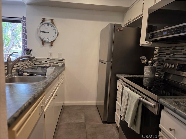 kitchen featuring appliances with stainless steel finishes, a sink, tasteful backsplash, and white cabinets