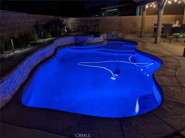 1800 Windermere Dr, Lancaster, CA 93534 - pool at night featuring a fenced backyard, a patio, and a pool with connected hot tub