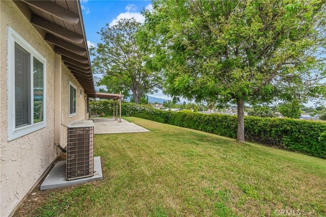view of grassy yard featuring a patio area and central AC