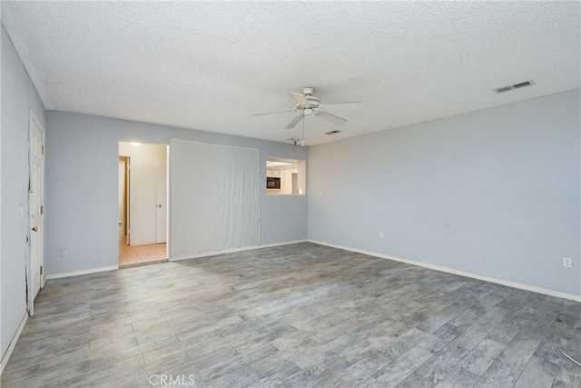 spare room with ceiling fan, wood finished floors, a textured ceiling, and baseboards