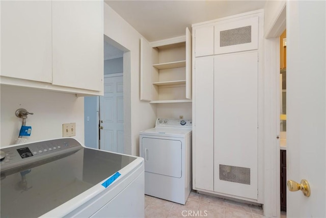 clothes washing area featuring separate washer and dryer, cabinet space, and light tile patterned floors