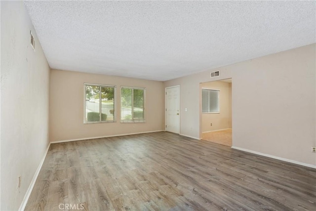 unfurnished room featuring a textured ceiling, wood finished floors, and baseboards