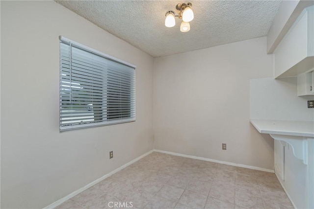 unfurnished dining area featuring a textured ceiling, light tile patterned floors, and baseboards