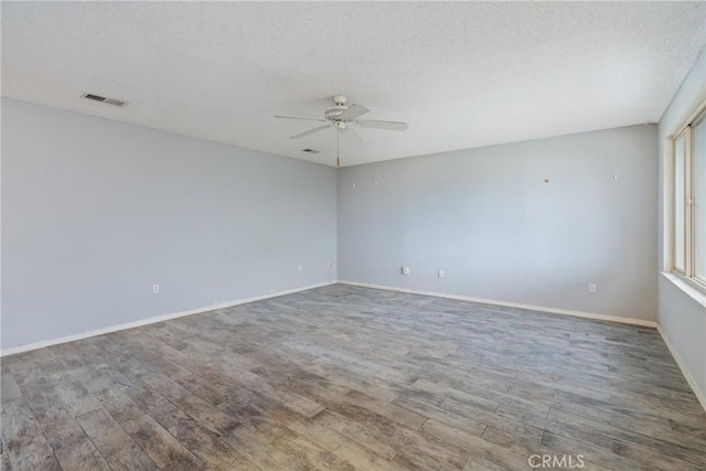 unfurnished room featuring ceiling fan, wood finished floors, baseboards, and a textured ceiling
