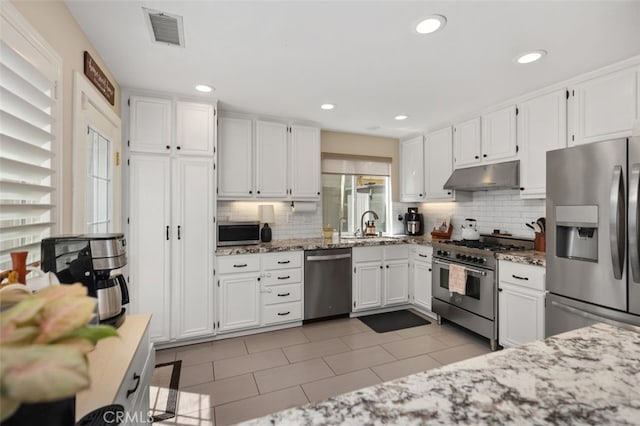 130 Bloomfield Ln, Rancho Santa Margarita, CA 92688 - kitchen with stainless steel appliances, under cabinet range hood, backsplash, white cabinetry, and light stone counters