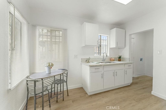 9309 S Broadway, Los Angeles, CA 90003 - kitchen with a sink, light countertops, light wood-style floors, white cabinetry, and baseboards
