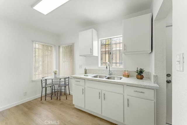 9309 S Broadway, Los Angeles, CA 90003 - kitchen featuring a sink, light wood-type flooring, white cabinets, and plenty of natural light
