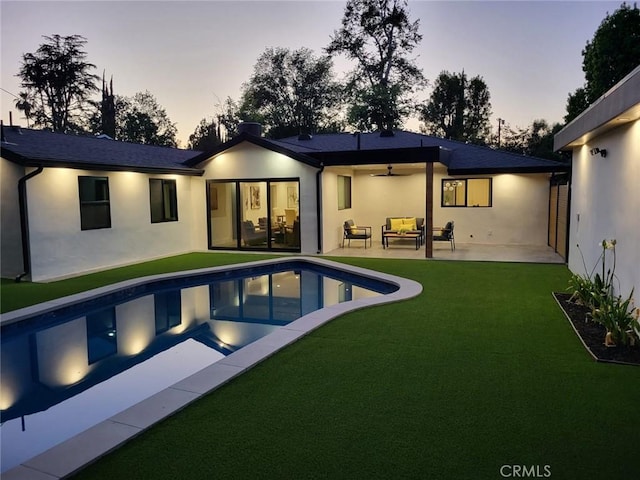 23240 Leonora Dr, Woodland Hills, CA 91367 - back of property at dusk with ceiling fan, an outdoor living space, stucco siding, a patio, and a yard
