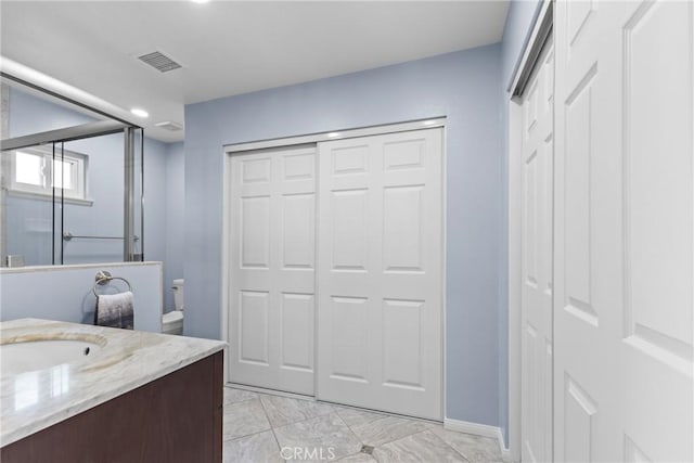 12705 Foreman Ave, Moreno Valley, CA 92553 - bathroom with vanity, a shower with door, marble finish flooring, baseboards, and toilet