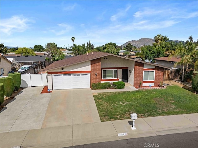 12705 Foreman Ave, Moreno Valley, CA 92553 - ranch-style house with brick siding, concrete driveway, an attached garage, a mountain view, and stucco siding
