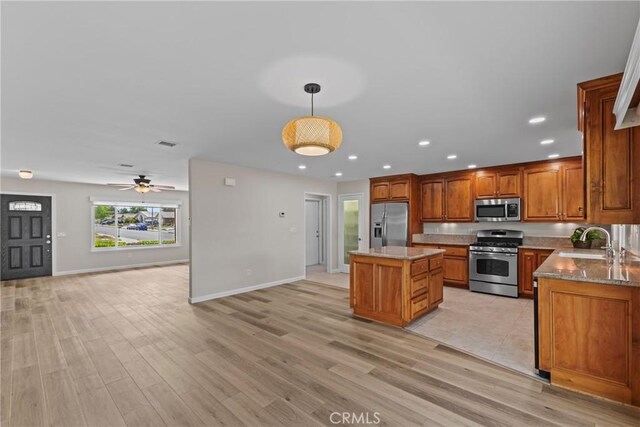 12705 Foreman Ave, Moreno Valley, CA 92553 - kitchen featuring stainless steel appliances, a sink, open floor plan, a center island, and brown cabinetry