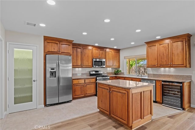 12705 Foreman Ave, Moreno Valley, CA 92553 - kitchen with stainless steel appliances, beverage cooler, a sink, brown cabinets, and recessed lighting