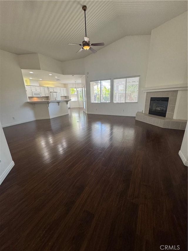 4809 Prairie Meadows Way, Bakersfield, CA 93312 - unfurnished living room with a ceiling fan, a tiled fireplace, dark wood-style flooring, vaulted ceiling, and baseboards