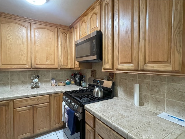 6 Rawhide Ln, Carson, CA 90745 - kitchen with stainless steel appliances, decorative backsplash, tile counters, and light tile patterned floors