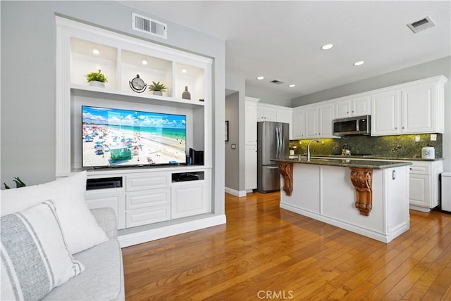 23423 Waterway Ln Unit 17, Valencia, CA 91355 - kitchen with appliances with stainless steel finishes, white cabinets, decorative backsplash, light wood finished floors, and recessed lighting