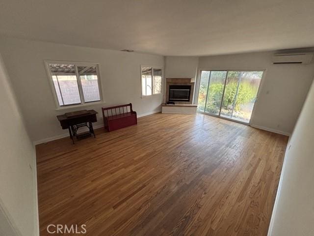 2020 W Swanee Ln, West Covina, CA 91790 - unfurnished living room featuring a wall mounted AC, wood finished floors, baseboards, and a glass covered fireplace