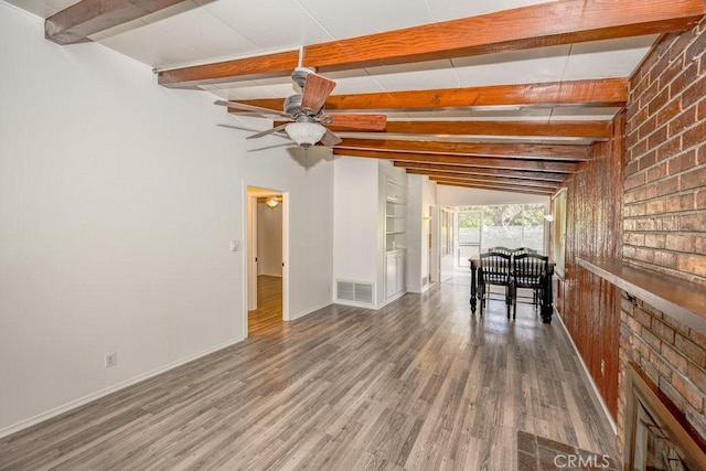 interior space with beam ceiling, wood finished floors, baseboards, and a ceiling fan