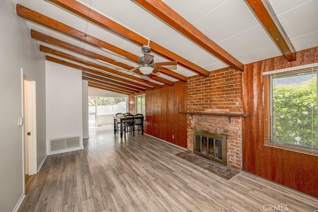 living area featuring ceiling fan, wood walls, wood finished floors, a fireplace, and baseboards