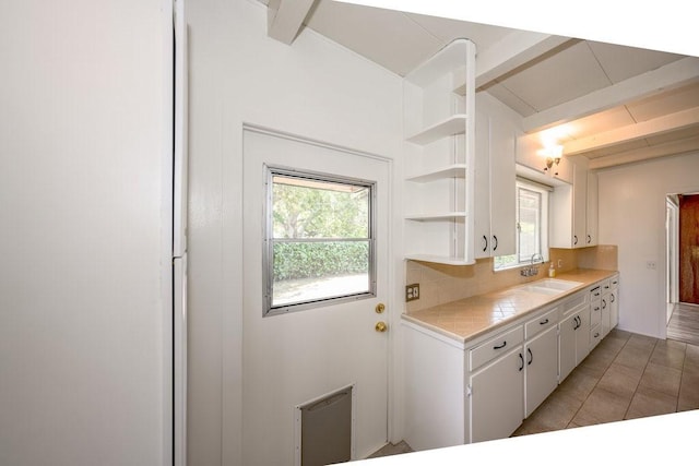 kitchen featuring beam ceiling, light countertops, white cabinetry, open shelves, and light tile patterned floors