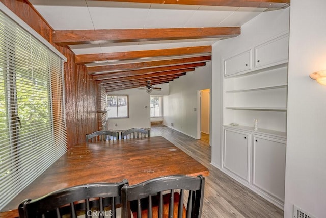 dining space with light wood-style flooring, a ceiling fan, beam ceiling, and baseboards