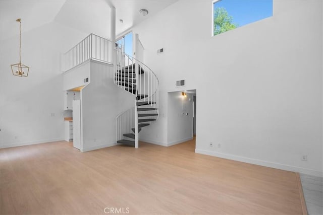 14937 Dickens St Unit 209, Sherman Oaks, CA 91403 - unfurnished living room with wood finished floors, stairs, a towering ceiling, baseboards, and a chandelier
